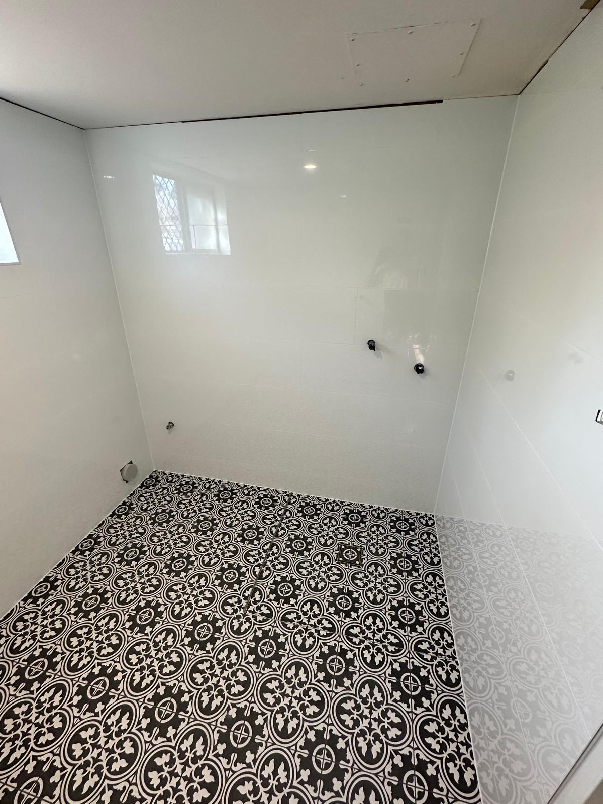 Black and white patterned bathroom floor tiles with plain white walls, before fit-out
